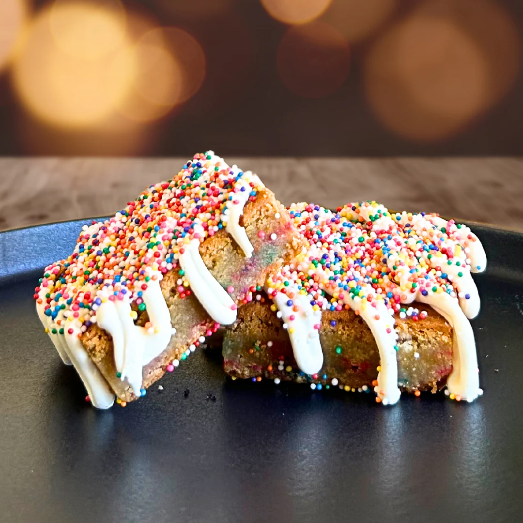 Celebration blondies covered in rainbow sprinkles and vanilla icing