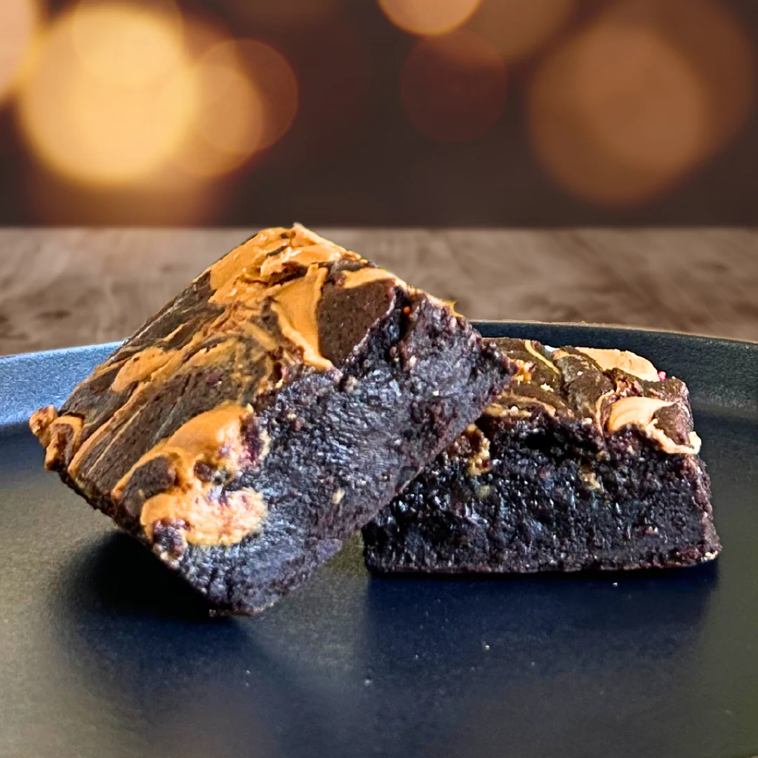Peanut butter brownies with thick peanut butter swirls on a dark plate