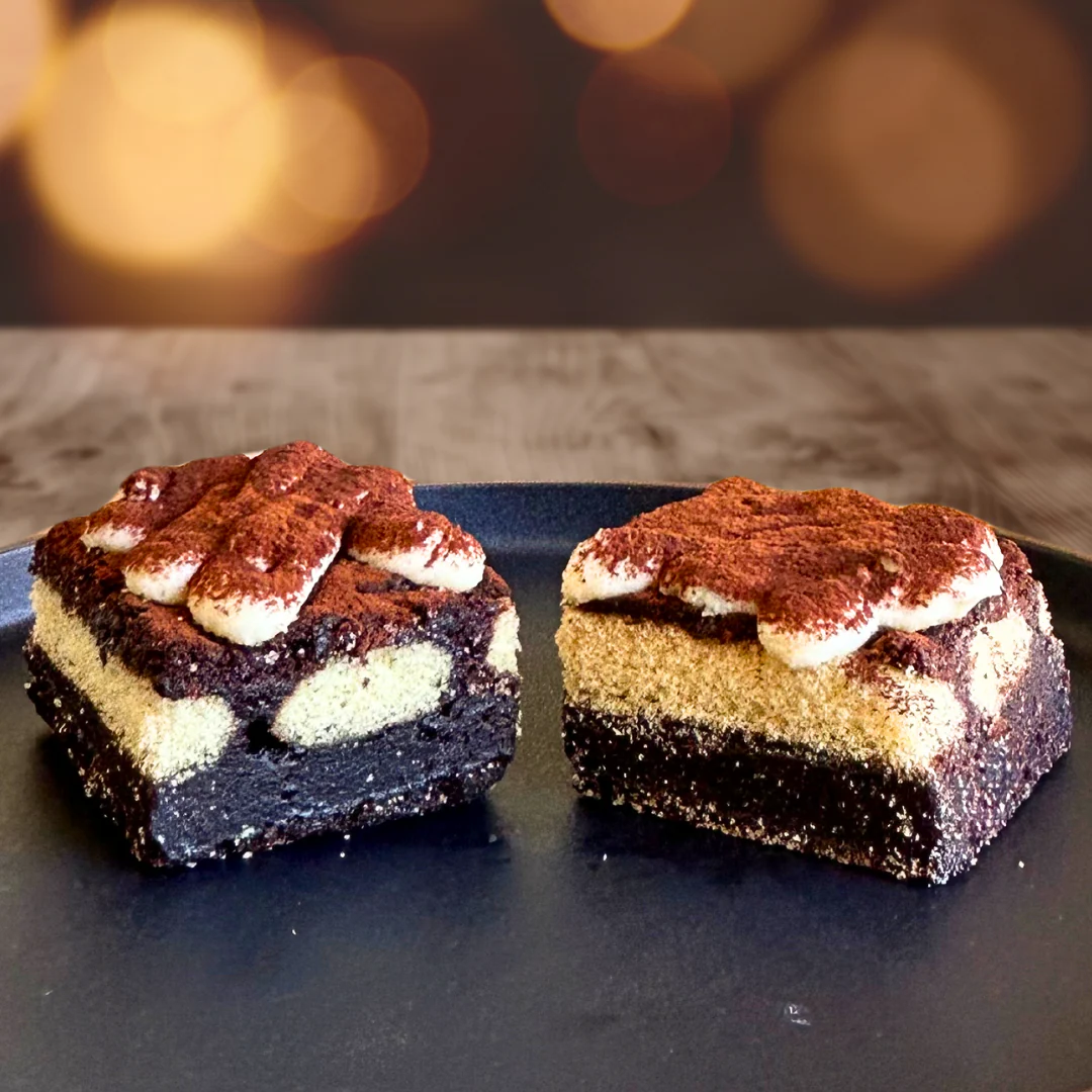 Tiramisu brownies layered with ladyfingers and dusted with cocoa